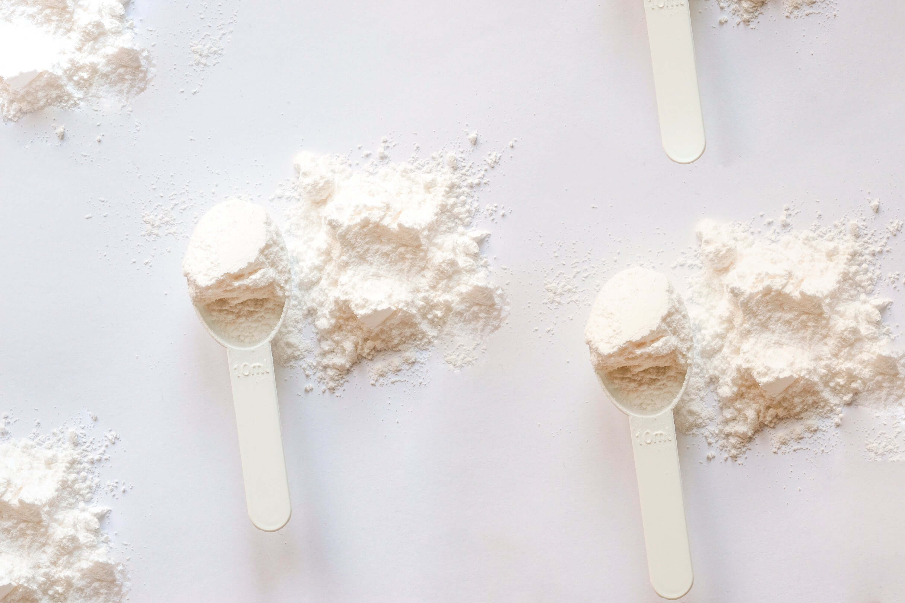 pre-workout supplement benefits: white powder in scoops for energy and performance enhancement.