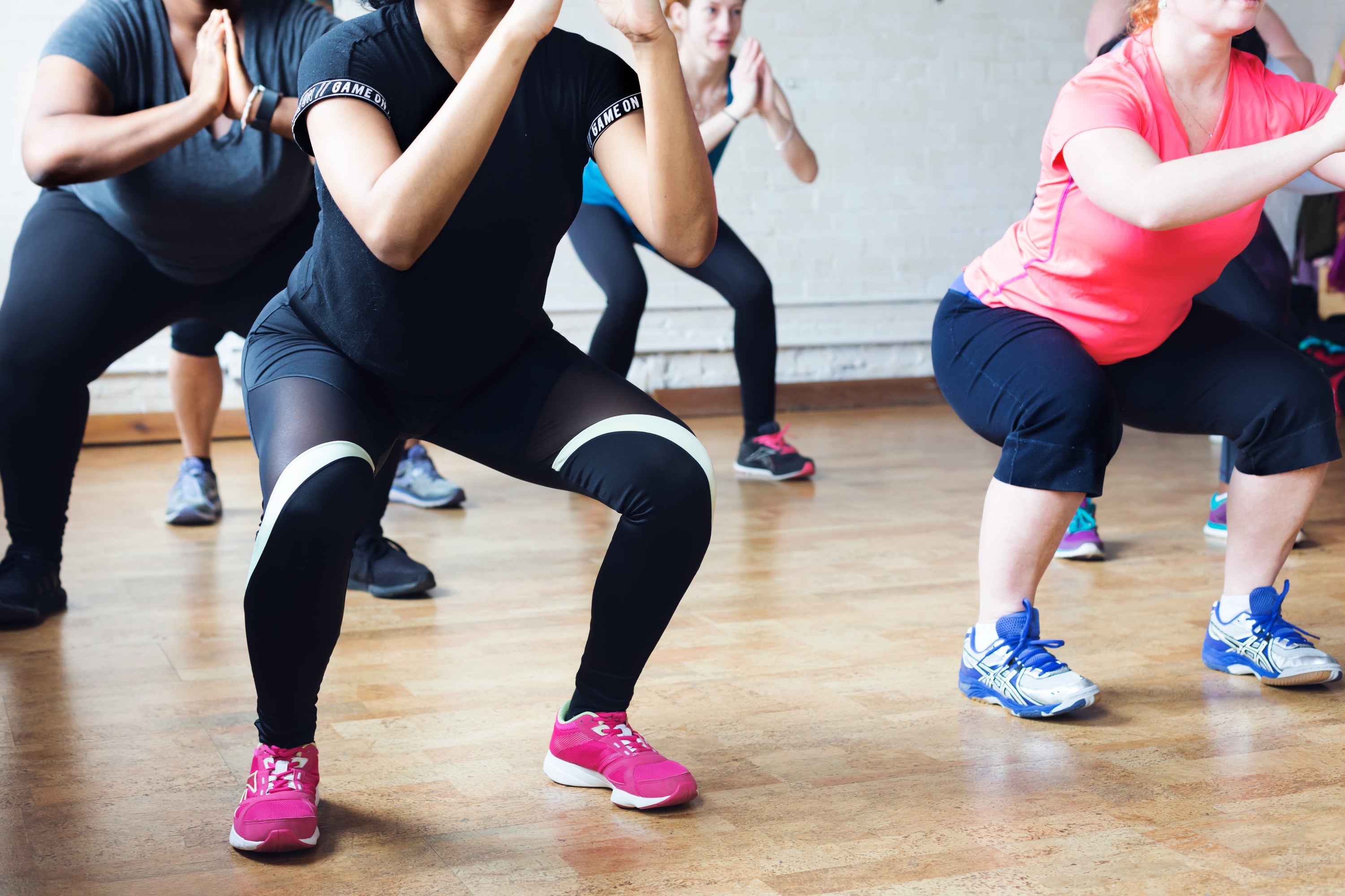Group of people exercising squats, showcasing essential home gym equipment in use for fitness training.