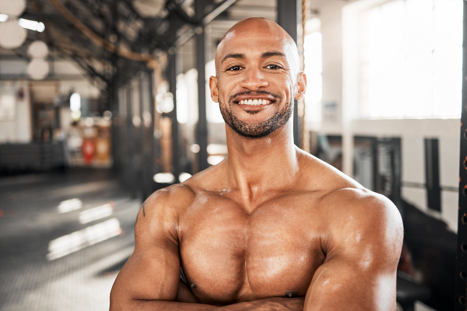 Smiling man with muscular build in gym, representing workouts that help you lose weight.
